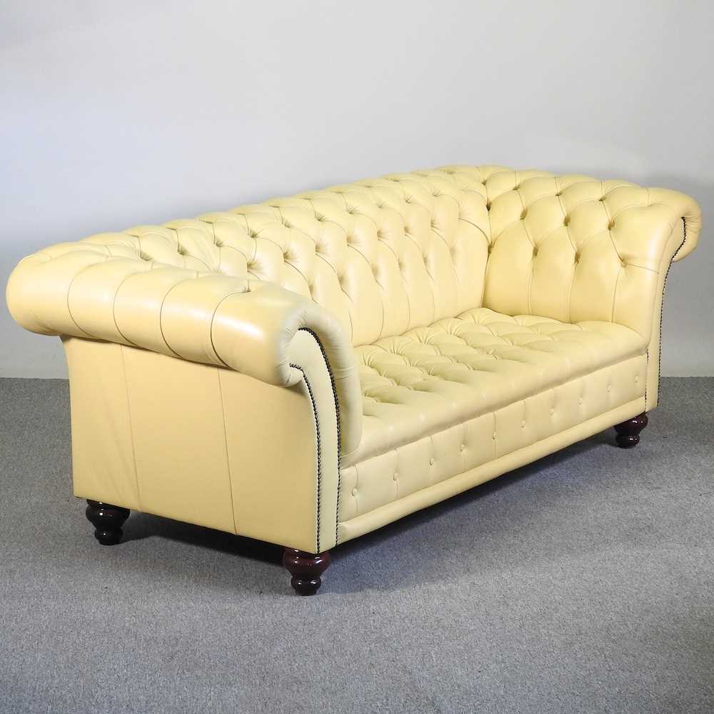 A modern cream leather upholstered chesterfield sofa, with a buttoned back, on turned legs 246w x