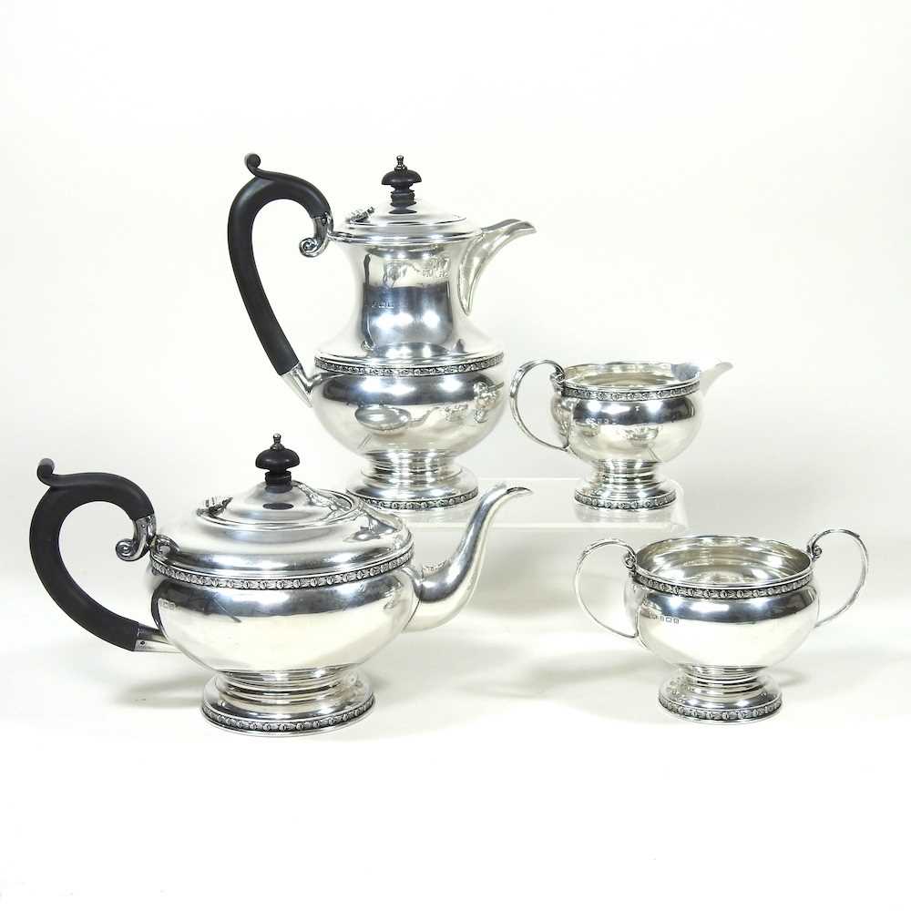 An early 20th century silver four piece tea service, of circular shape, with ebonised handles and