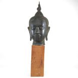 An Eastern bronze life-sized Buddha head, probably 20th century, mounted on a wooden base, 73cm high