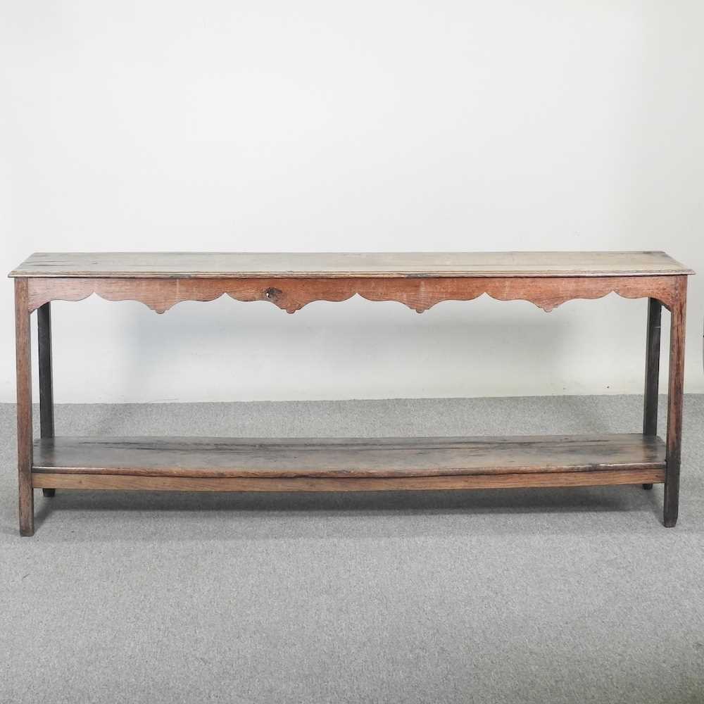 An 18th century Welsh dresser base, of narrow proportions, with an undulating frieze, on square