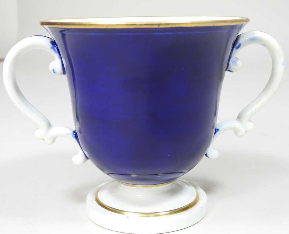 An early 19th century Derby porcelain twin handled cup, reserved with a river landscape, on a blue - Image 2 of 7