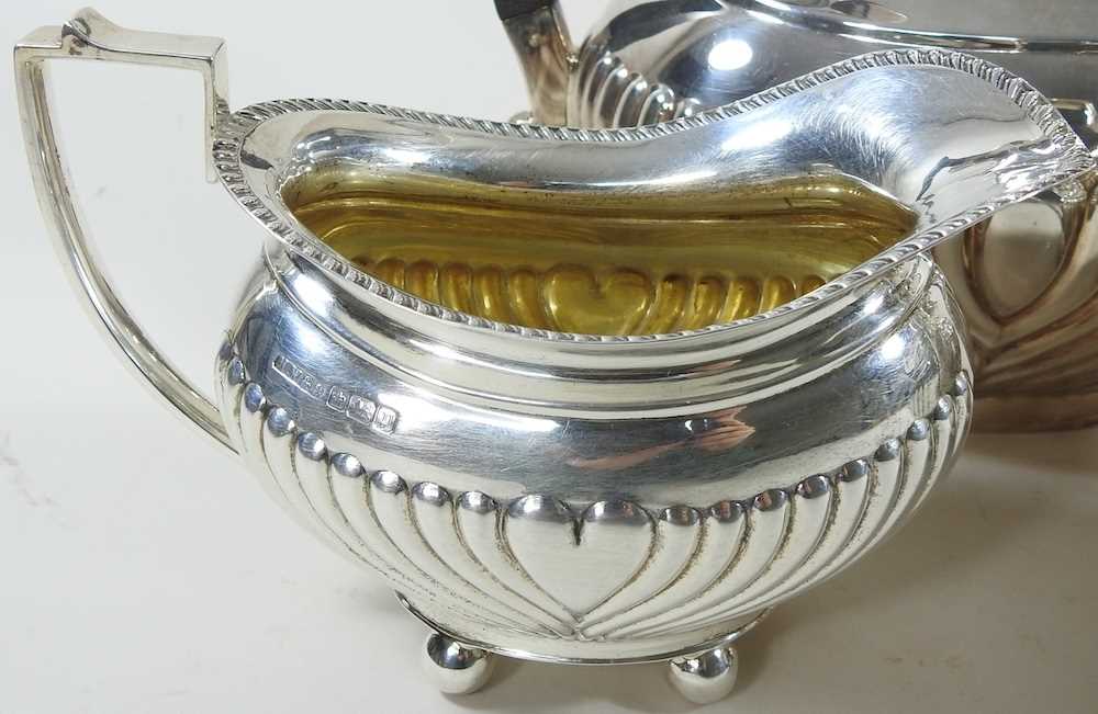 An Edwardian silver three piece tea service, with half gadrooned decoration, comprising a teapot, - Image 4 of 9