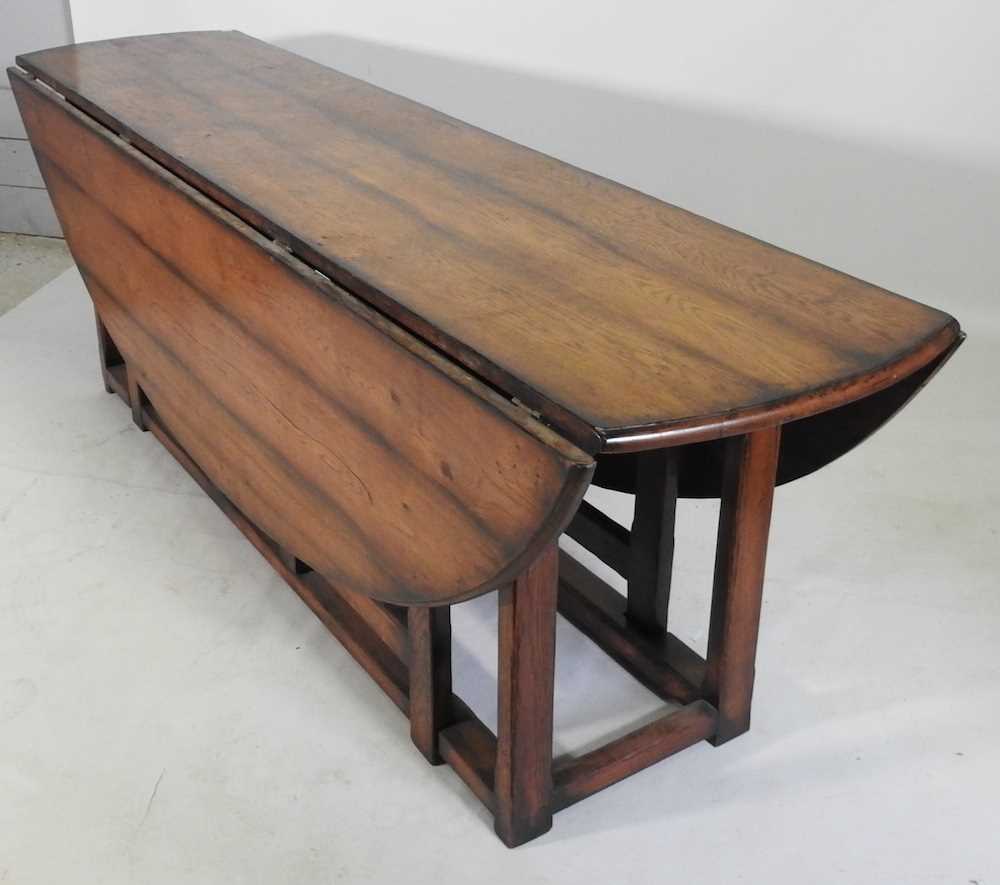 A large 18th century style oak wakes table, 20th century, the hinged oval top with a double gateleg, - Image 3 of 5