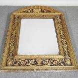 An ornate early 20th century continental carved wood and gilt cushion framed wall mirror, with a