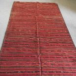 A Persian kilim, with striped designs, on a red ground, 370 x 162cm