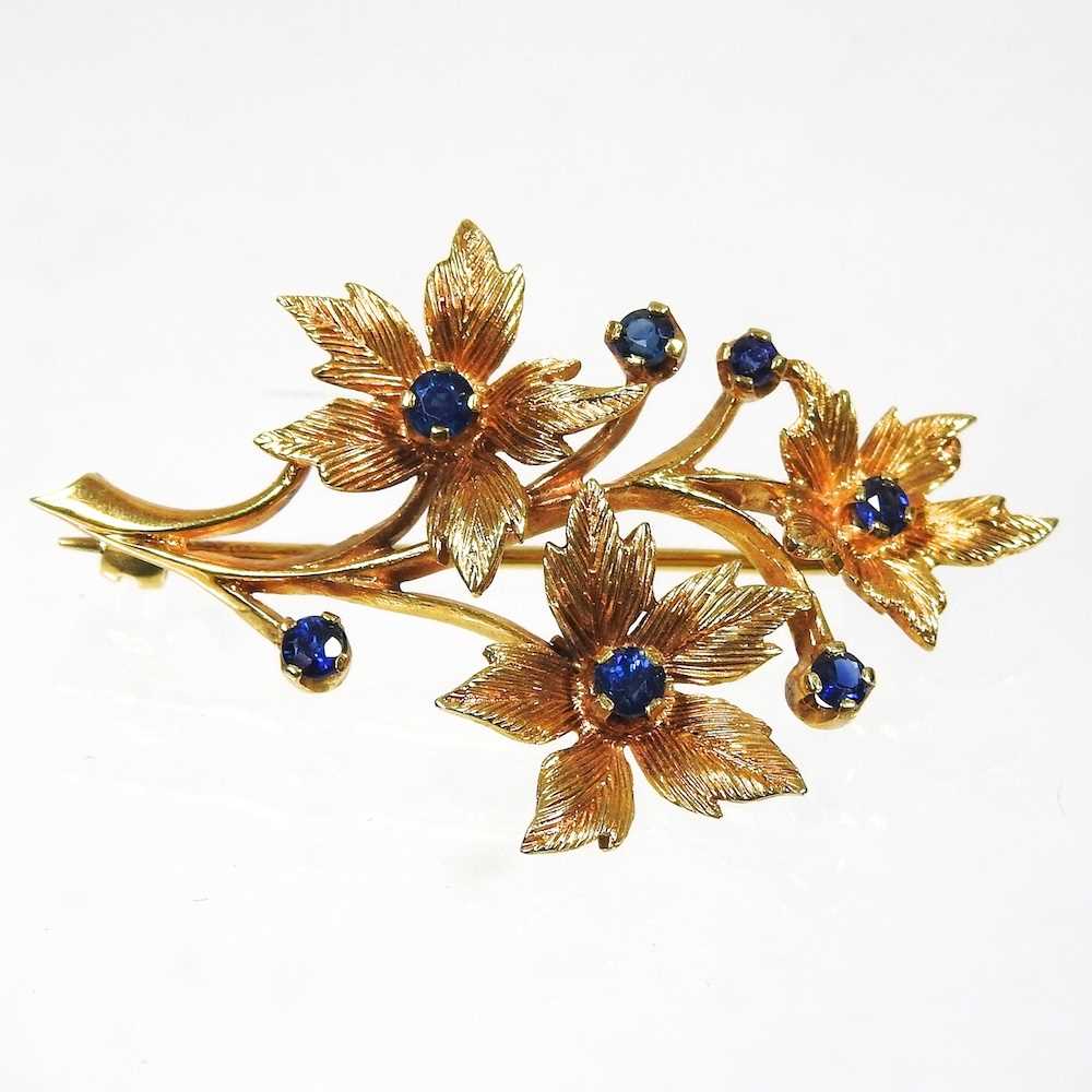 A 9 carat gold and sapphire brooch, in the form of a floral spray, 7.1g, 45mm wide, cased
