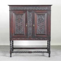 An early 20th century carved oak cabinet, on stand, on spirally turned legs 115w x 57d x 138h cm