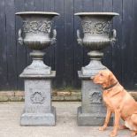 A pair of impressive black painted cast iron garden urns, each of classical design, with an acanthus