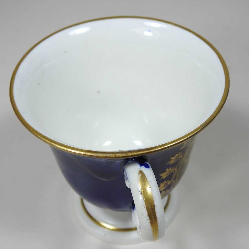 An early 19th century Derby porcelain twin handled cup, reserved with a river landscape, on a blue - Image 4 of 7