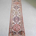 A Persian runner, with a row of central medallions, 307 x 72cm