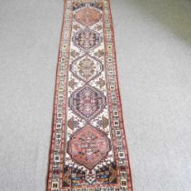 A Persian runner, with a row of central medallions, 307 x 72cm