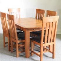 A modern light oak extending dining table, with a set of six dining chairs with brown leather