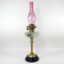 A 19th century brass oil lamp, with a cranberry glass chimney, 65cm high Cranberry chimney is