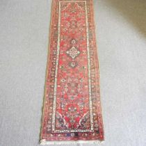 A Persian runner, with foliate designs, on a red ground, 310 x 88cm