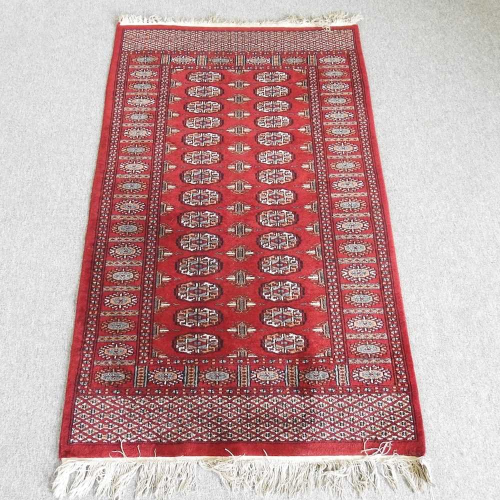 A Bokhara woollen rug, with two rows of medallions, on a red ground, 160 x 92cm