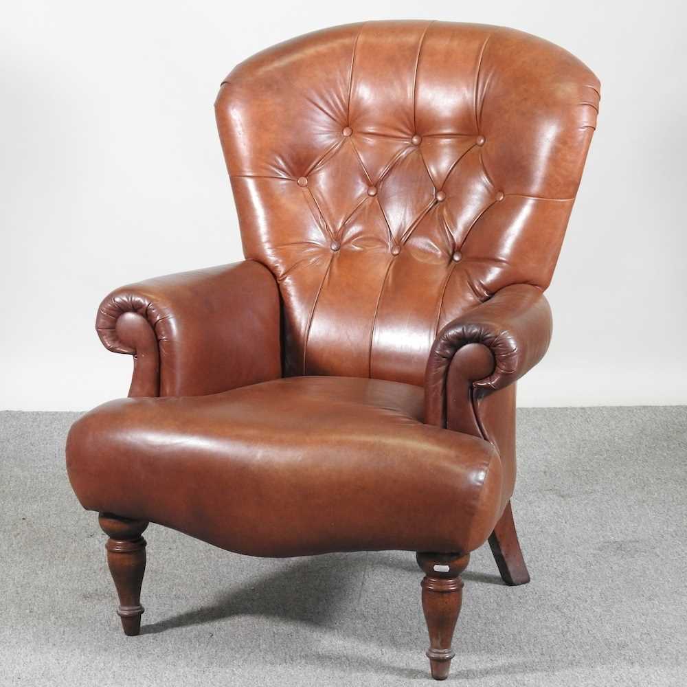 A modern brown leather upholstered button back armchair, on turned legs