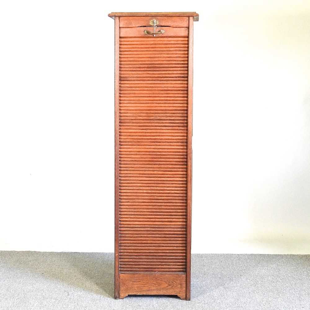 An early 20th century oak tambour front filling cabinet, on a plinth base 46w x 39d x 151h cm