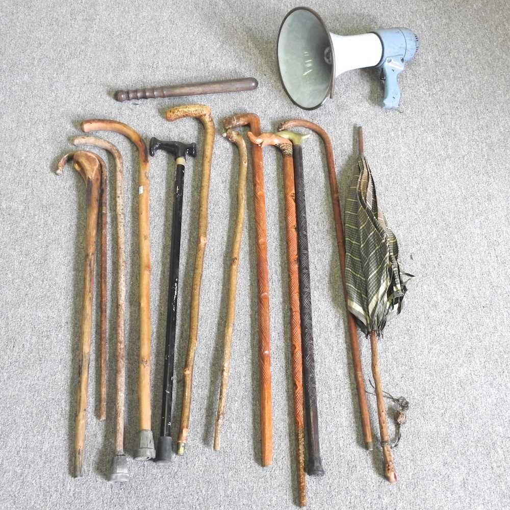 A collection of walking sticks, together with a truncheon and a vintage loud hailer