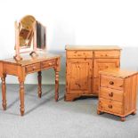 A pine cabinet, 89cm wide, together with a pine bedside cabinet and a pine dressing table, with