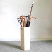 A stick stand containing a collection of walking sticks and a shooting stick