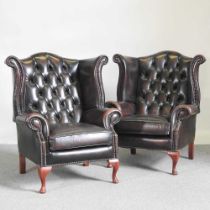 A pair of brown leather upholstered button back wing armchairs, on cabriole legs (2)