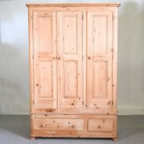 An antique pine triple wardrobe, with drawers below 130w x 58d x 192h cm