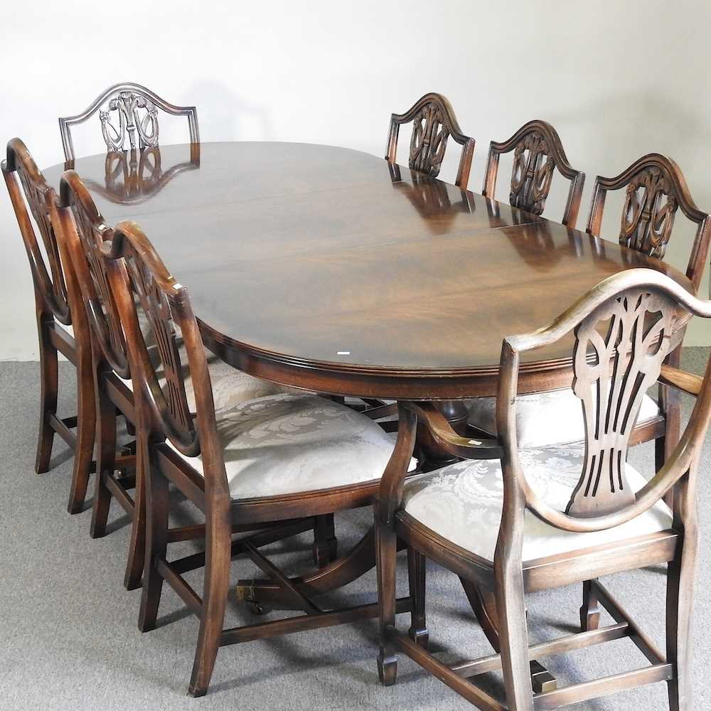 A reproduction mahogany dining suite, comprising a dining table and set of eight Hepplewhite style