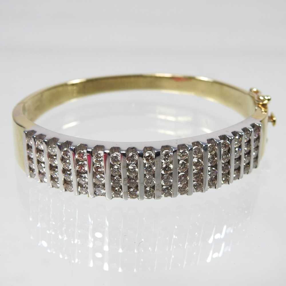 A 14 carat gold and diamond bangle, of hinged design, set with seventeen rows of four diamonds,