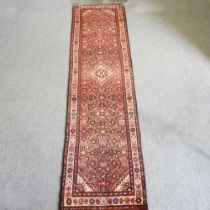 A Persian malayer runner, with flowerhead motifs, on a red ground, 308 x 85cm