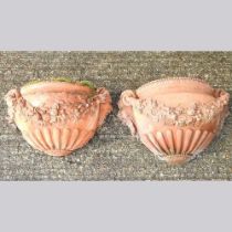 A pair of terracotta stone wall pockets, decorated with festoons of flowers, 42cm wide (2)