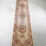 A Persian runner, with a row of central medallions, on a cream ground, 300 x 75cm