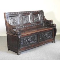 A 19th century Dutch heavily carved dark oak box settle, the panelled back carved with tavern