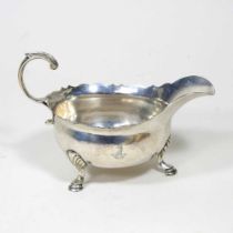 A George II silver sauce boat, of helmet shape, with a flying scrolled handle, on hoof feet,