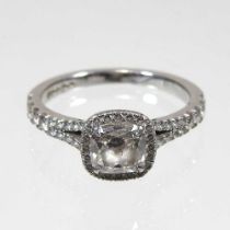 A platinum and diamond halo ring, the central brilliant cut stone approximately one carat, colour D,