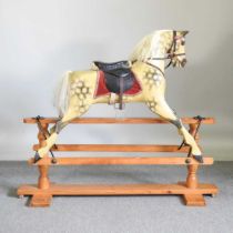 A mid 20th century carved wooden dappled grey rocking horse, on a trestle base 153w x 122h cm