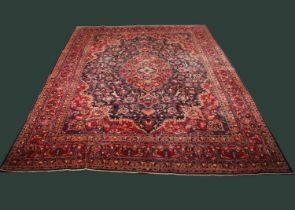 A large Persian Tabriz woollen rug, the central blue floral medallion upon a red ground with