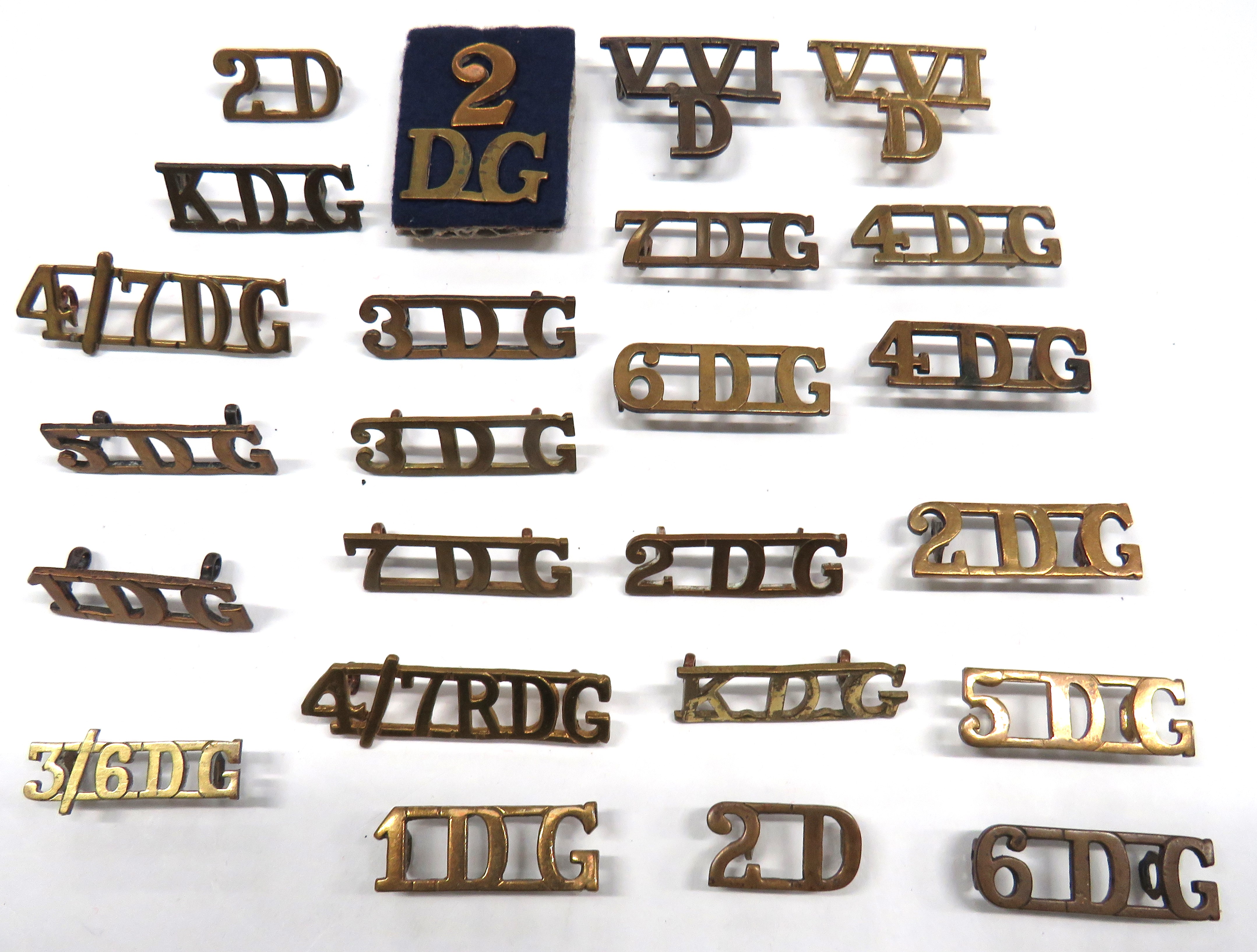 24 x Dragoon Guards Brass Shoulder Titles including KDG ... 1DG ... 2D ... 2DG (2 part) ... 2DG ..