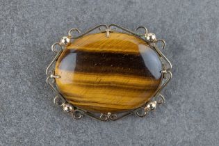 A 14ct yellow gold and tiger's eye brooch the 40 x 30mm. tiger's eye within a scroll and bead