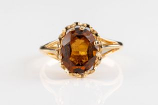 A 9ct yellow gold and citrine ring The oval cut dark citrine claw set to spilt shoulders and