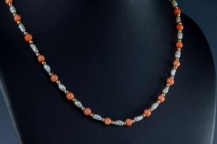 A coral and pearl necklace The necklace with alternating round coral beads, yellow metal beads and