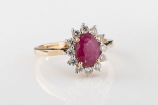 A ruby and diamond cluster ring The central oval-cut ruby in a surround of twelve brilliant-cut