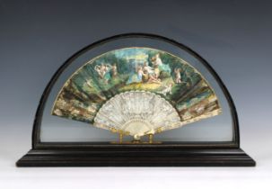 An ornate folding hand fan the sticks intricately carved, leaf with classical figures, housed in a