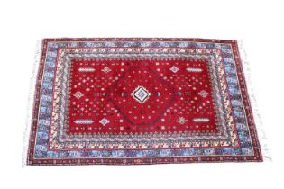 A modern Persian style wool rug with pendant medallion on a deep red ground with filler motif,