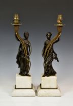 A pair of French patinated and gilt bronze figural candlesticks in the manner of Francois Remond,