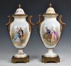 A pair of Sevres style porcelain urn shaped lidded vases ormolu mounted, hand painted with elegant