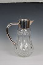 A 20th century clear cut glass water jug with silver plated lid and handle of large proportions,