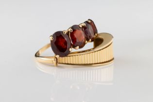 A 14ct yellow gold and garnet dress ring The four oval cut graduated garnets above a fluted