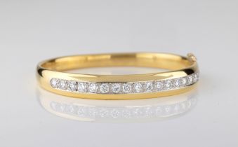 A fine 18ct gold and diamond bangle import marks for London 1990, the heavy, hinged bangle of