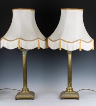 A pair of brass table lamps in the form of Corinthian columns, with shades, 22½ inches tall (57cm)