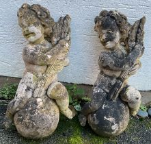 A pair of composite stone Putti each depicting a figure raised on a sphere holding aloft a sheaf